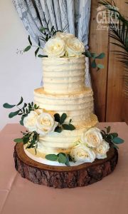 Three tier ribbed buttercream white fresh roses greenery wedding cake