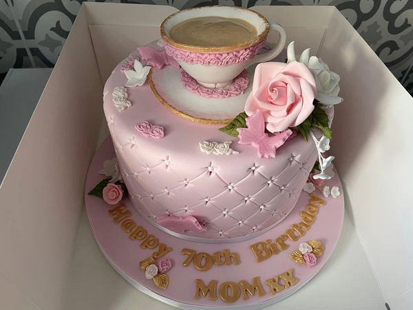 Pink 70th birthday cake with icing in shape of a cup of tea