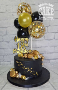 black and gold birthday cake with balloon cake topper